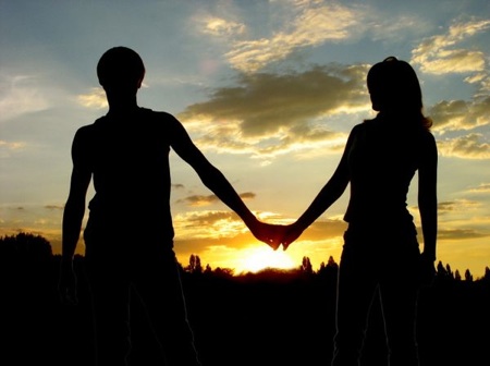 Loving couple holdind on the hands and sunset