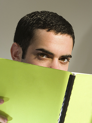Male student hiding behind a book